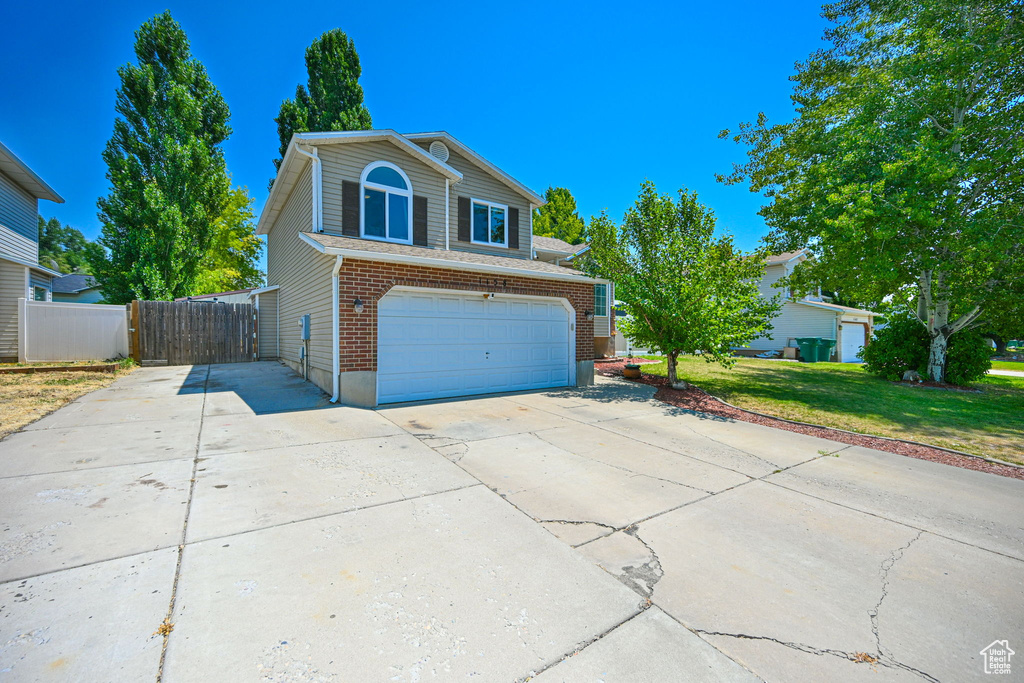 View of front facade featuring a garage and a front lawn