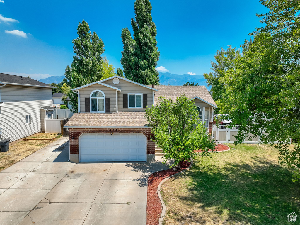 View of front of house featuring a garage, a front lawn, and a mountain view