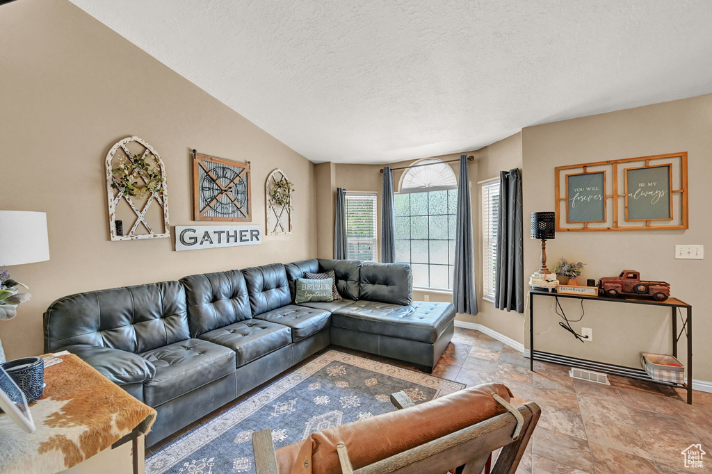 Living room featuring tile patterned flooring, vaulted ceiling, and a textured ceiling