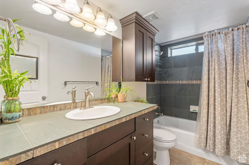 Full bathroom featuring vanity, shower / bath combo with shower curtain, tile patterned flooring, and toilet