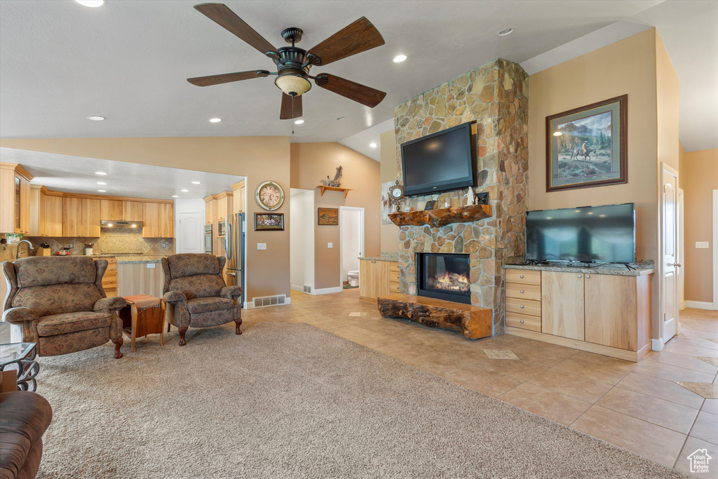 Tiled living room featuring a stone fireplace, vaulted ceiling, sink, and ceiling fan