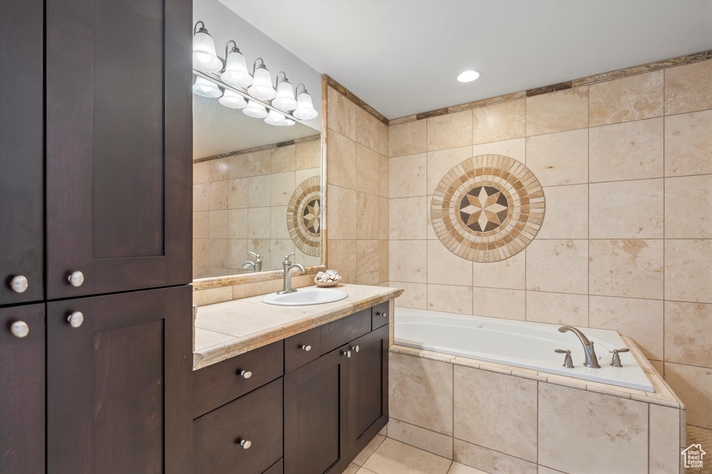 Bathroom with vanity, tile patterned floors, tile walls, and a relaxing tiled tub