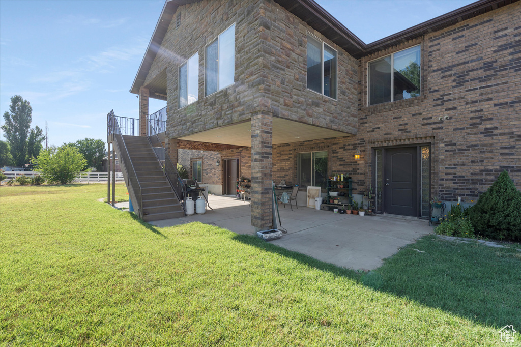 Rear view of house with a patio and a yard