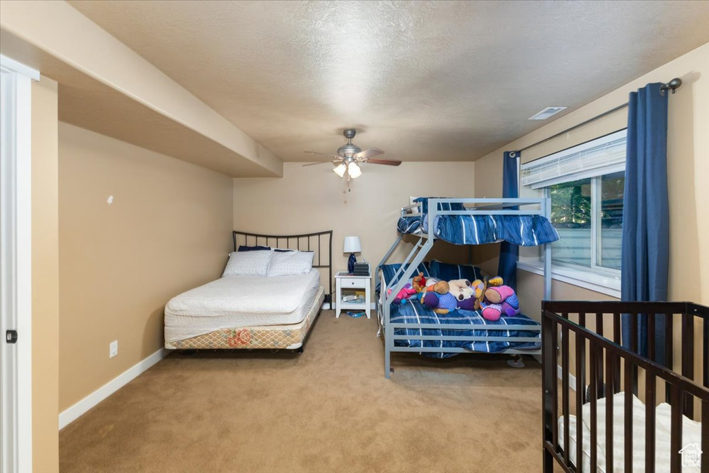 Bedroom featuring carpet, a textured ceiling, and ceiling fan