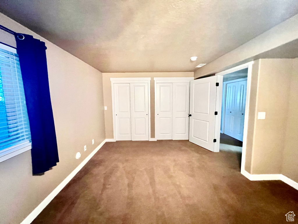 Unfurnished bedroom featuring carpet floors and two closets