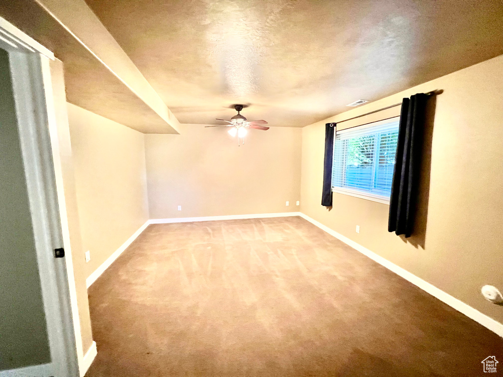 Carpeted spare room featuring ceiling fan and a textured ceiling