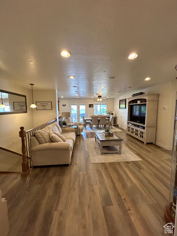 Living room with a textured ceiling, ceiling fan, and wood-type flooring