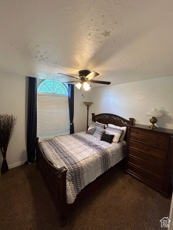 Carpeted bedroom featuring a textured ceiling and ceiling fan