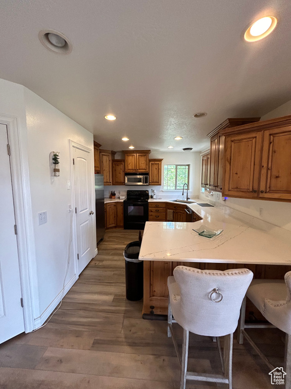 Kitchen featuring a breakfast bar, kitchen peninsula, dark hardwood / wood-style floors, stainless steel appliances, and sink