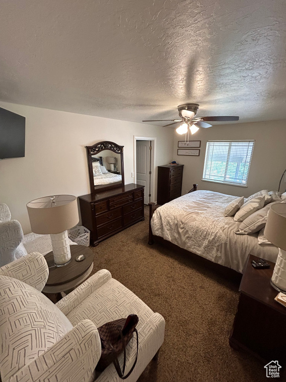 Bedroom with a textured ceiling, dark colored carpet, and ceiling fan