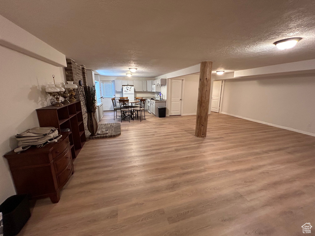 Living room featuring brick wall, light hardwood / wood-style flooring, and a textured ceiling