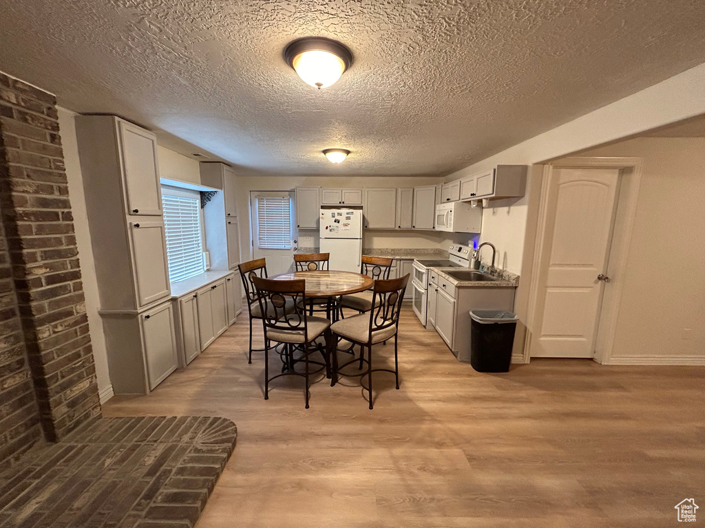 Dining area featuring sink, a textured ceiling, and light wood-type flooring