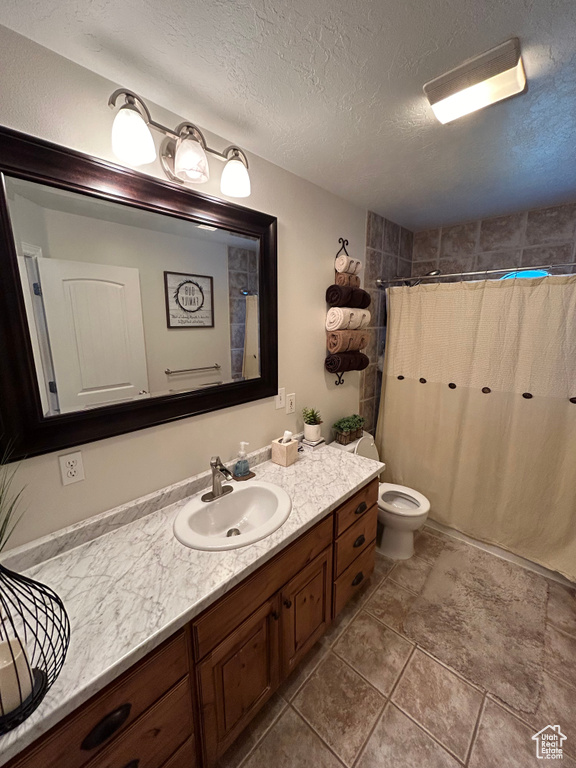 Bathroom with tile patterned flooring, toilet, vanity, and a textured ceiling