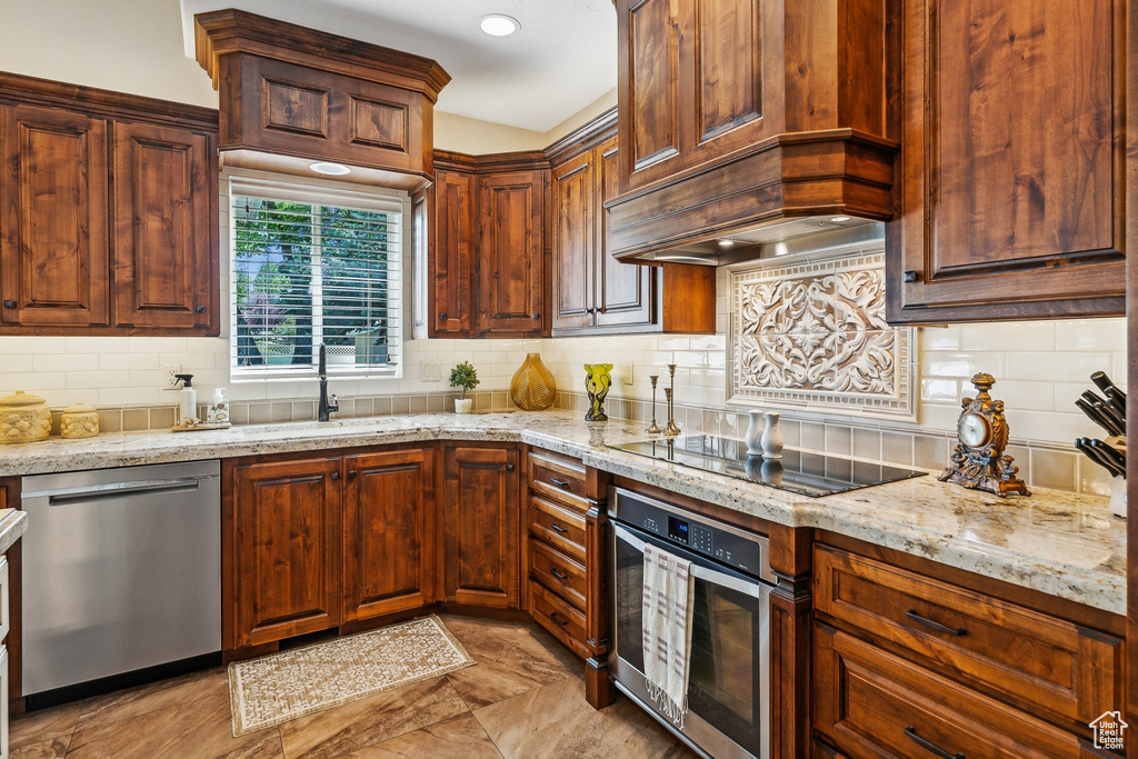 Kitchen featuring light tile patterned flooring, stainless steel appliances, tasteful backsplash, and sink