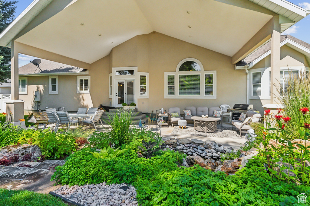 Back of property featuring an outdoor living space with a fire pit and a patio