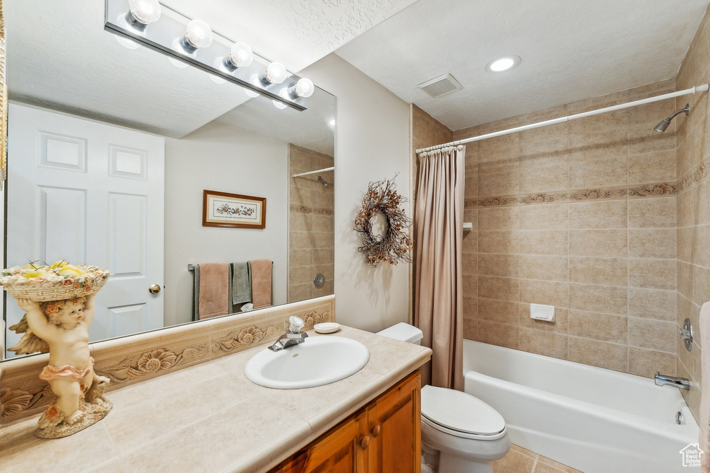 Full bathroom featuring vanity, shower / bathtub combination with curtain, tile patterned flooring, and toilet