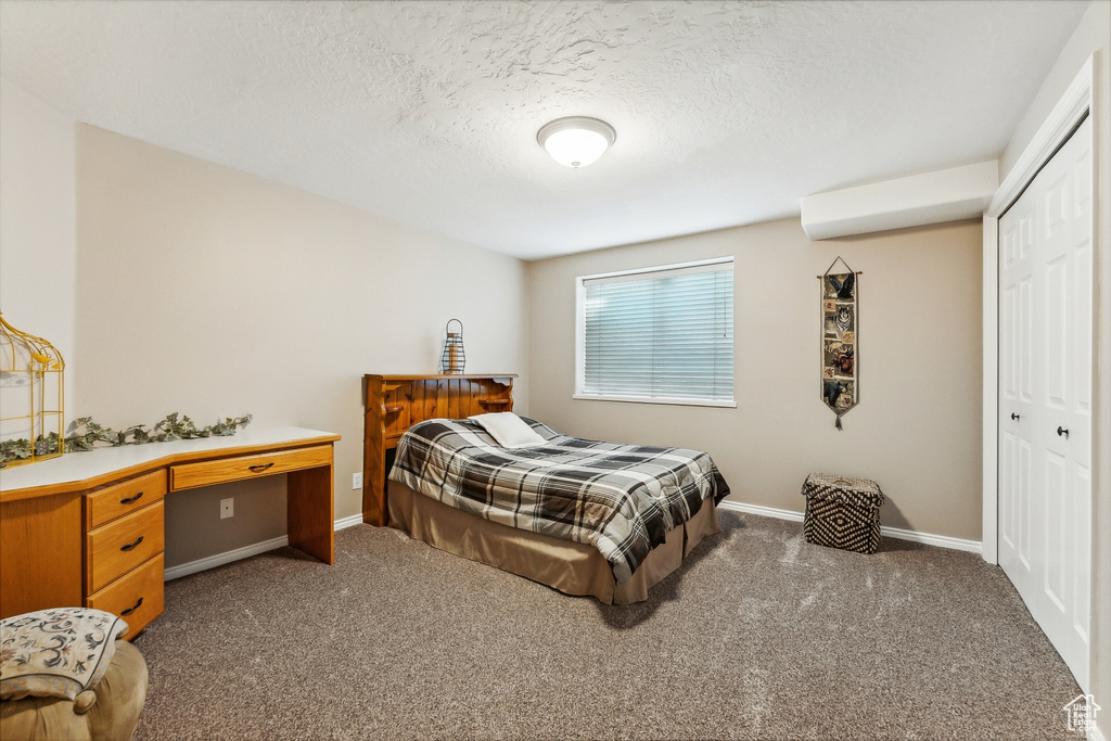 Bedroom with carpet, a closet, and a textured ceiling