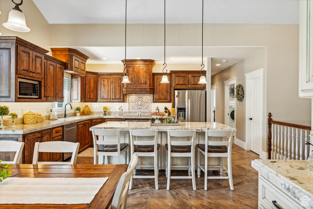 Kitchen featuring a center island, stainless steel appliances, decorative backsplash, pendant lighting, and sink