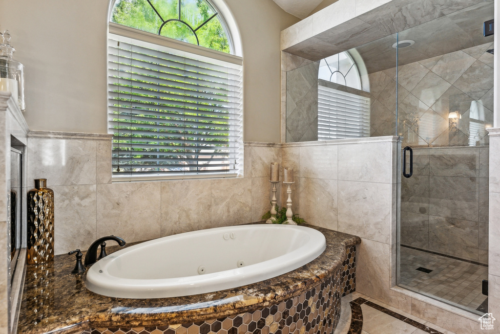 Bathroom featuring independent shower and bath, tile patterned flooring, and tile walls