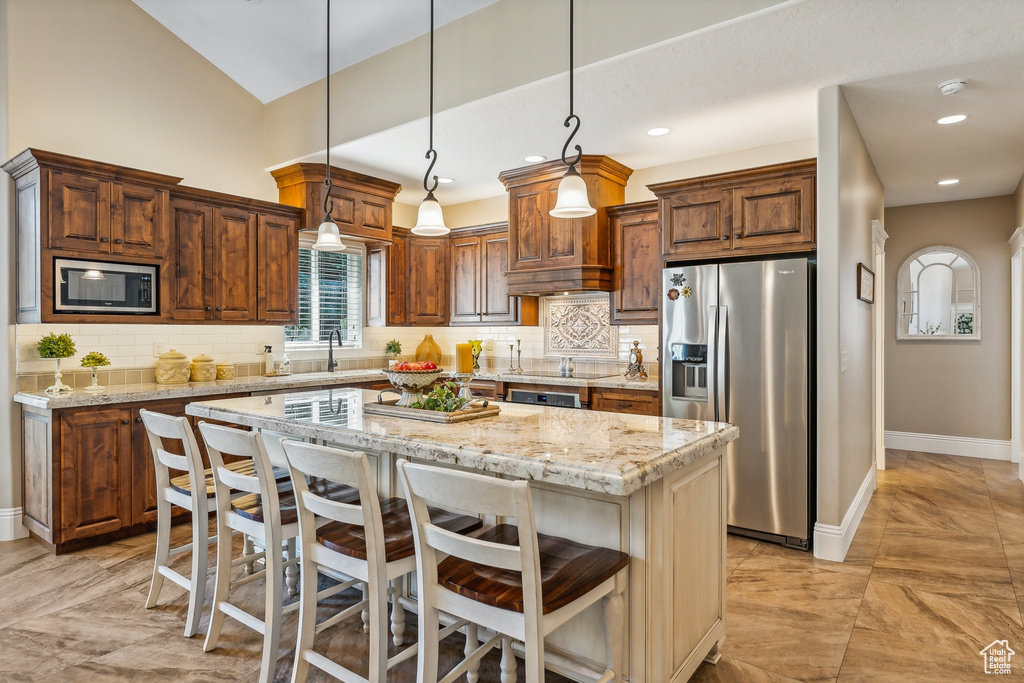 Kitchen with light tile patterned flooring, a kitchen island, stainless steel appliances, decorative backsplash, and sink