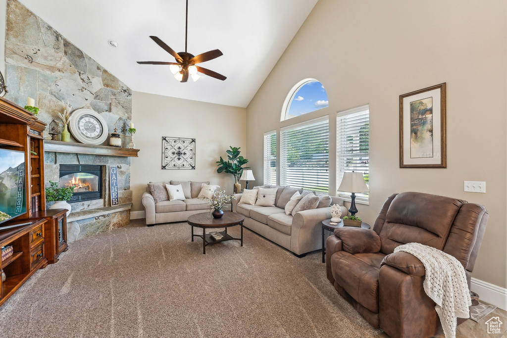 Living room featuring a stone fireplace, carpet floors, ceiling fan, and high vaulted ceiling