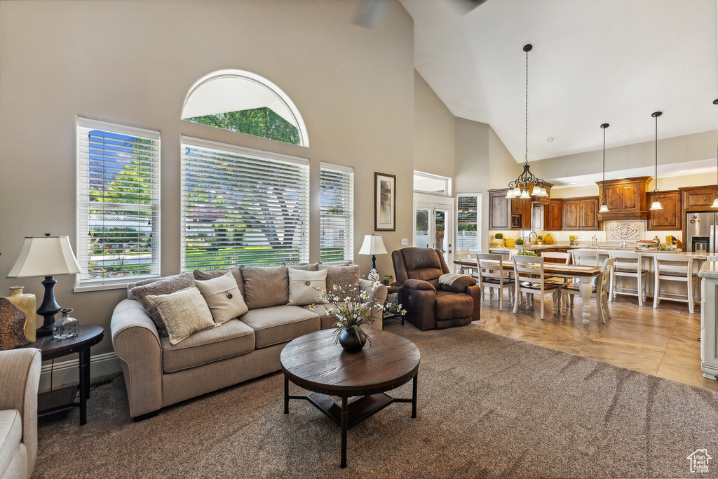 Living room featuring an inviting chandelier, light tile patterned floors, and a high ceiling