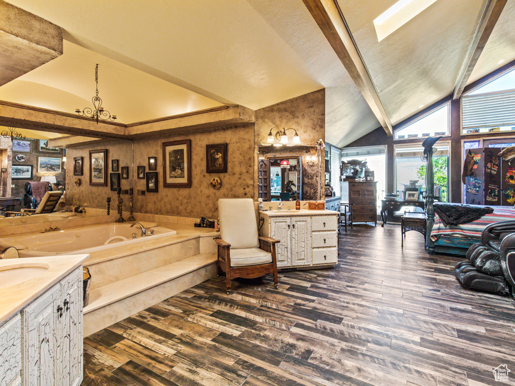 Bathroom with a bathtub, a skylight, vanity, hardwood / wood-style flooring, and high vaulted ceiling