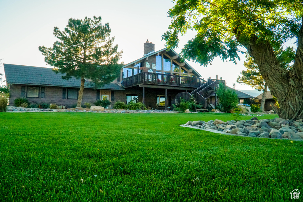 Rear view of property featuring a wooden deck and a lawn