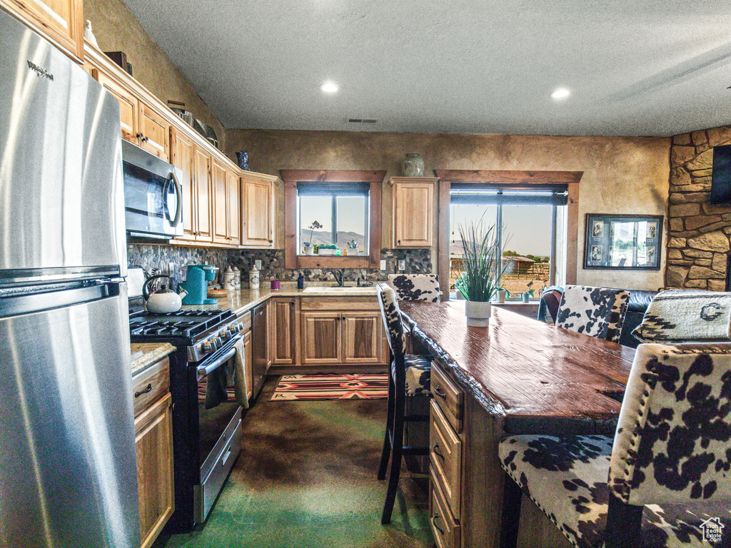 Kitchen featuring sink, appliances with stainless steel finishes, a textured ceiling, and tasteful backsplash