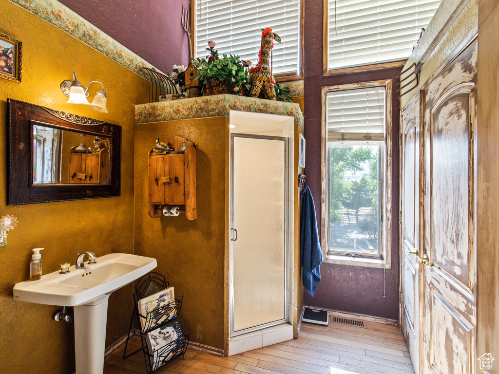 Bathroom with an enclosed shower, sink, and wood-type flooring