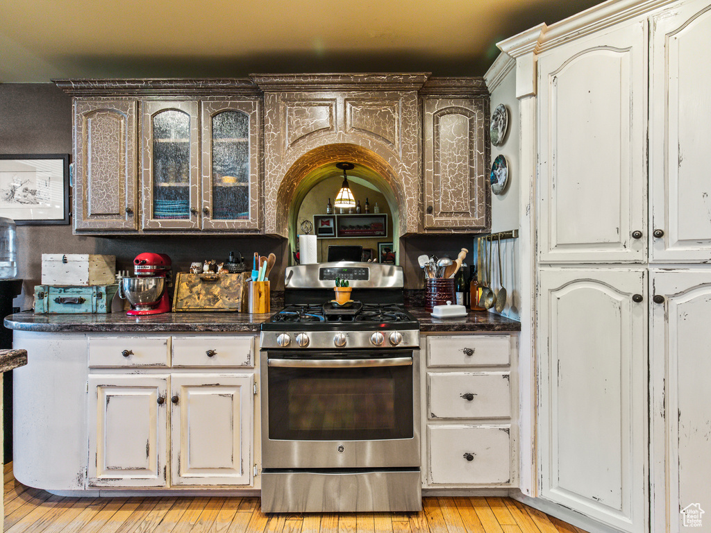 Kitchen featuring light hardwood / wood-style floors, dark stone counters, and gas stove