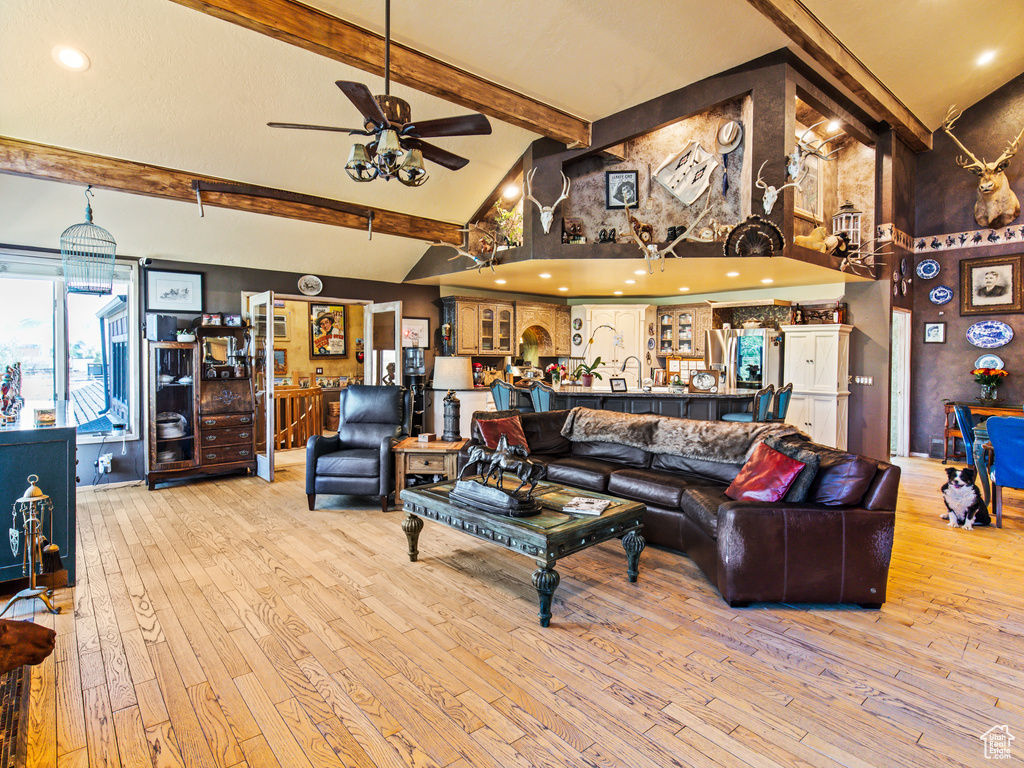 Living room featuring light hardwood / wood-style flooring, ceiling fan, and high vaulted ceiling