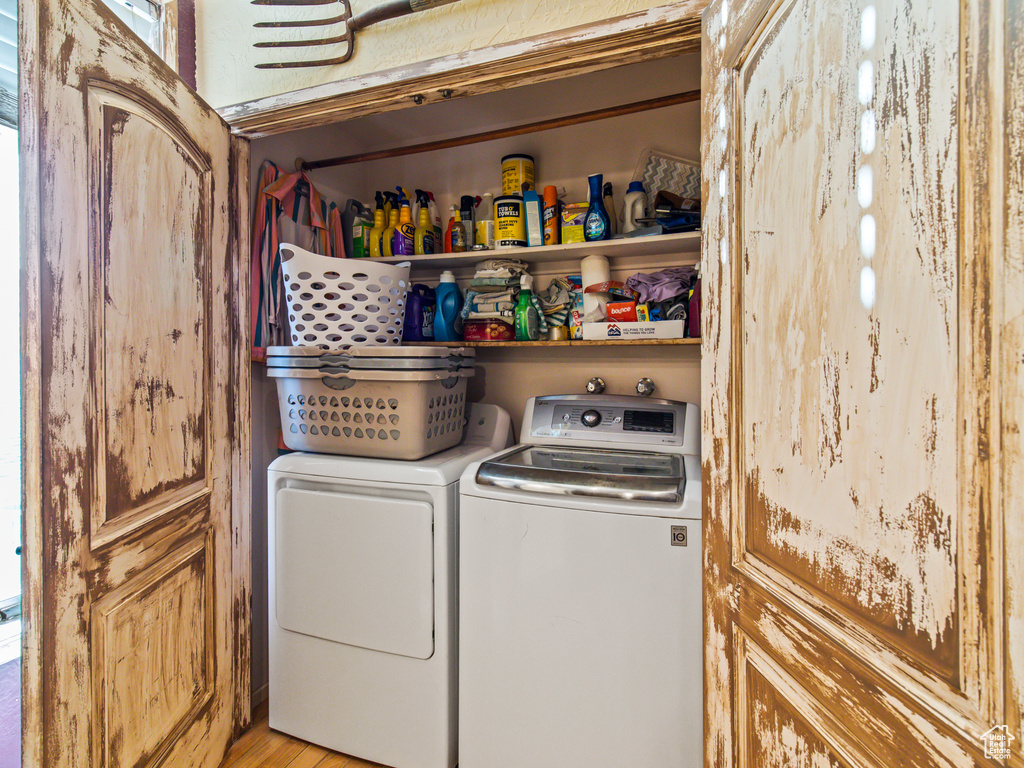 Laundry room with separate washer and dryer and light hardwood / wood-style flooring