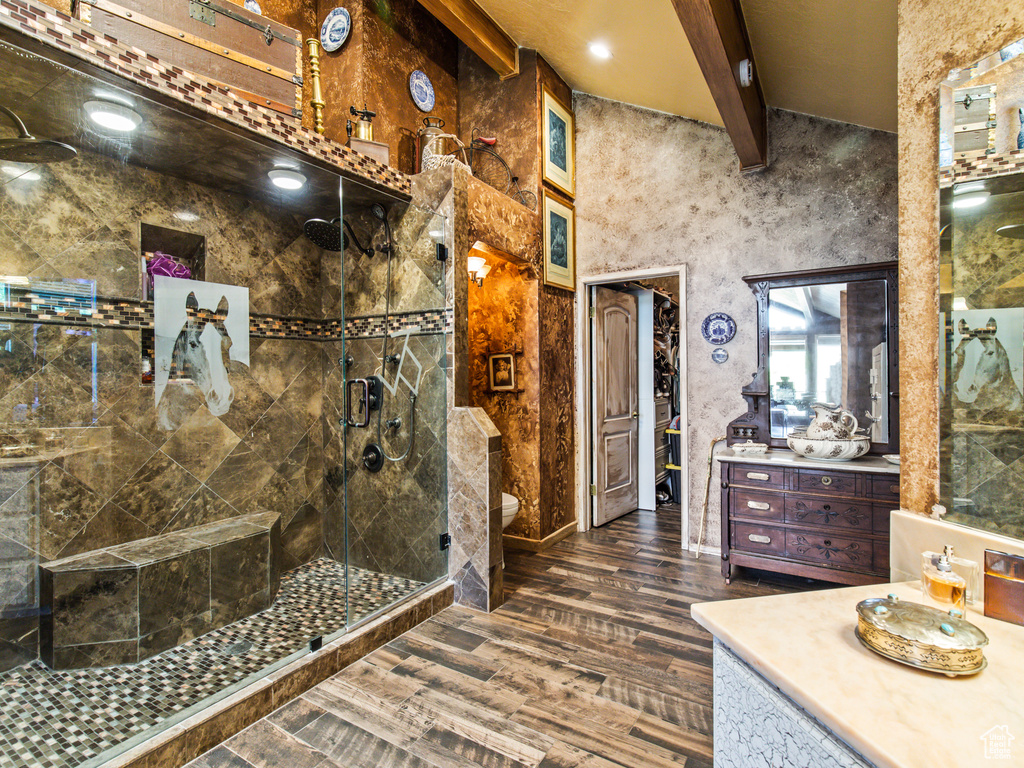 Bathroom featuring beam ceiling, a shower with door, toilet, vanity, and hardwood / wood-style floors