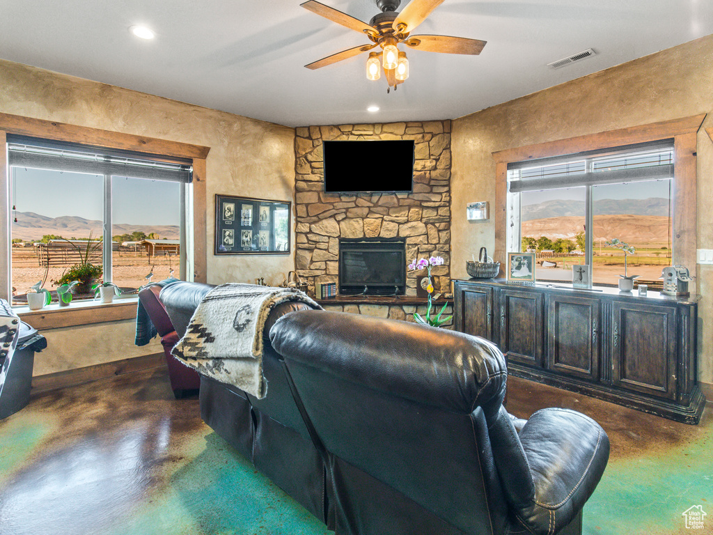 Living room with a mountain view, a stone fireplace, and ceiling fan