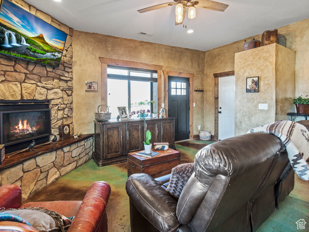 Carpeted living room with a fireplace and ceiling fan