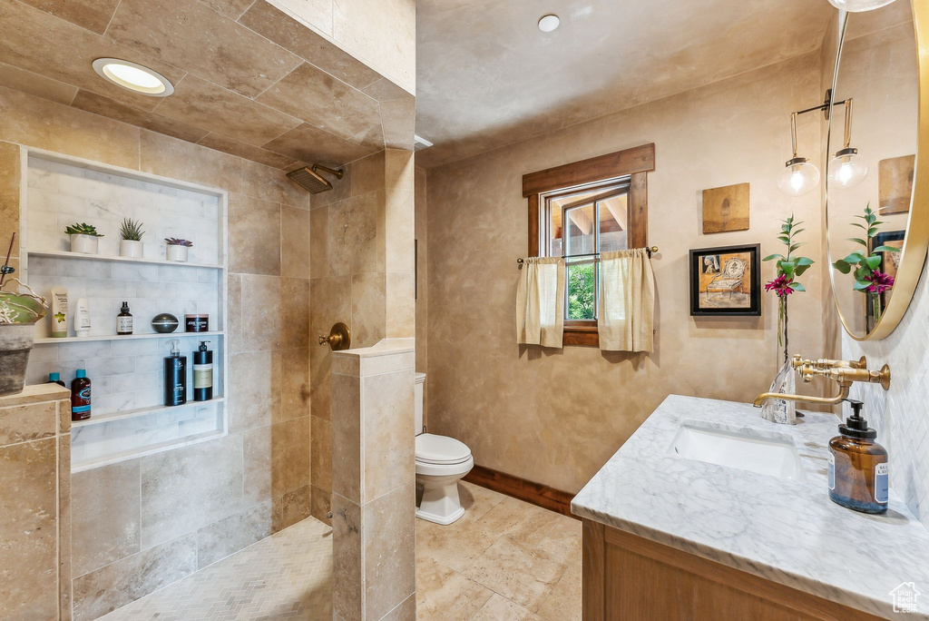 Bathroom with tile patterned floors, vanity, a tile shower, and toilet