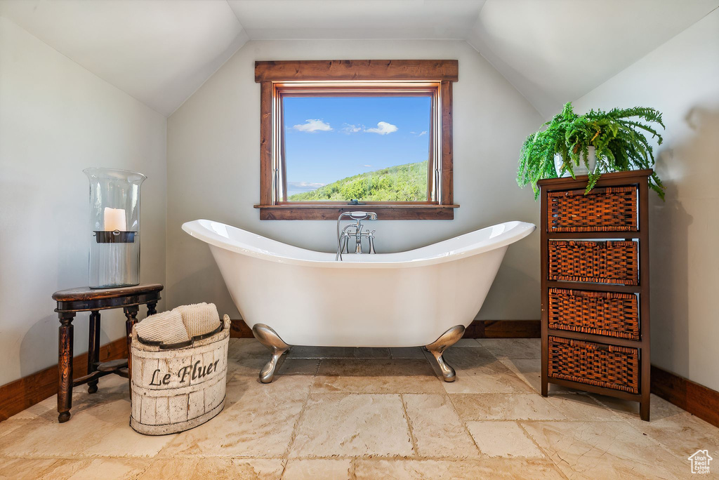 Bathroom with tile patterned floors, a bathtub, and vaulted ceiling