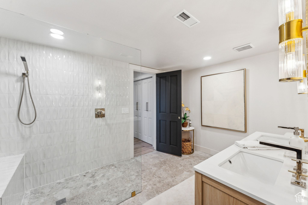 Bathroom featuring tiled shower, hardwood / wood-style flooring, and dual bowl vanity