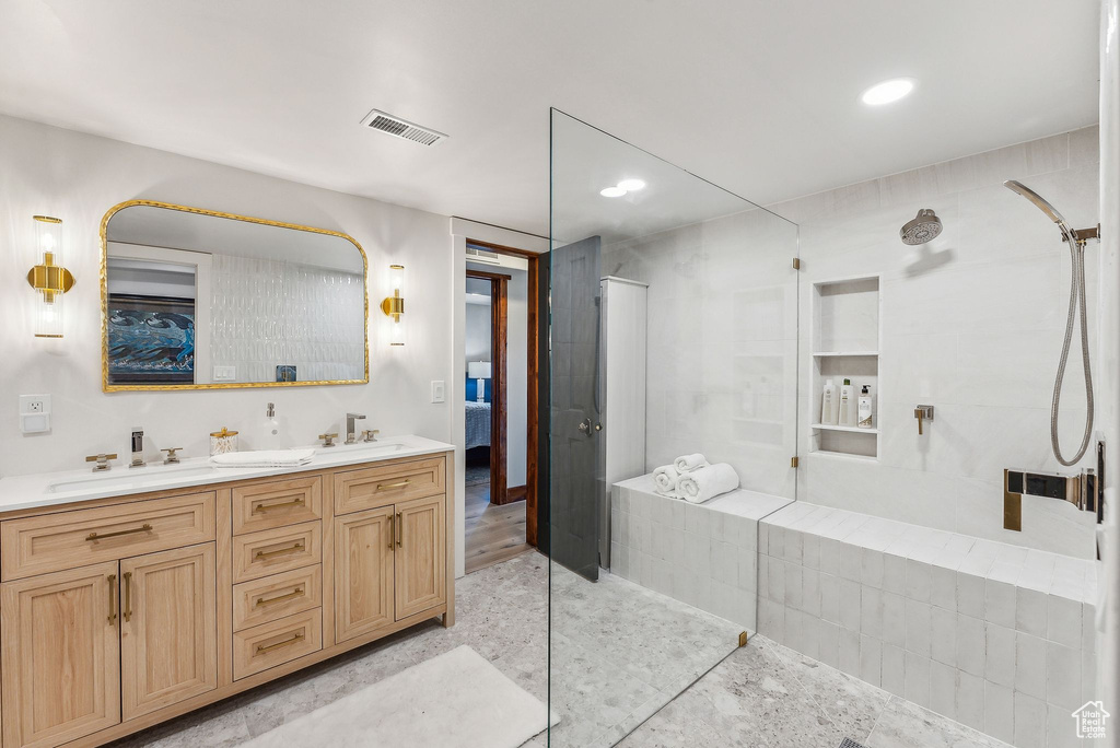 Bathroom with dual vanity, a tile shower, and tile patterned floors