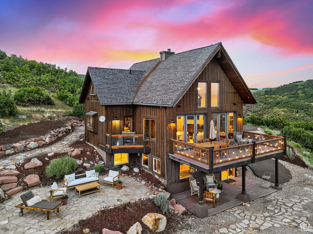 Back house at dusk with a patio, an outdoor hangout area, and a deck