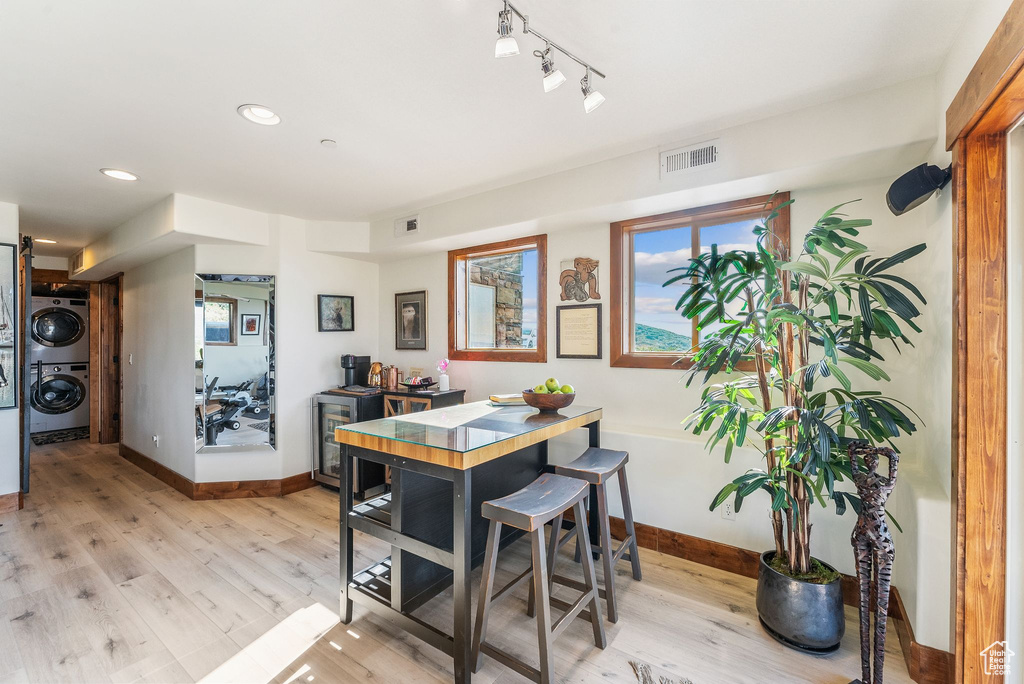 Dining space featuring stacked washer and clothes dryer, rail lighting, and light wood-type flooring