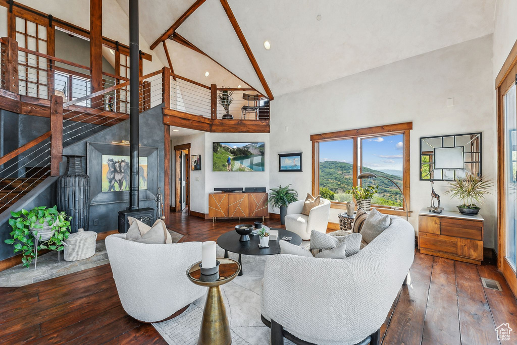 Living room featuring high vaulted ceiling, dark hardwood / wood-style floors, and a wood stove