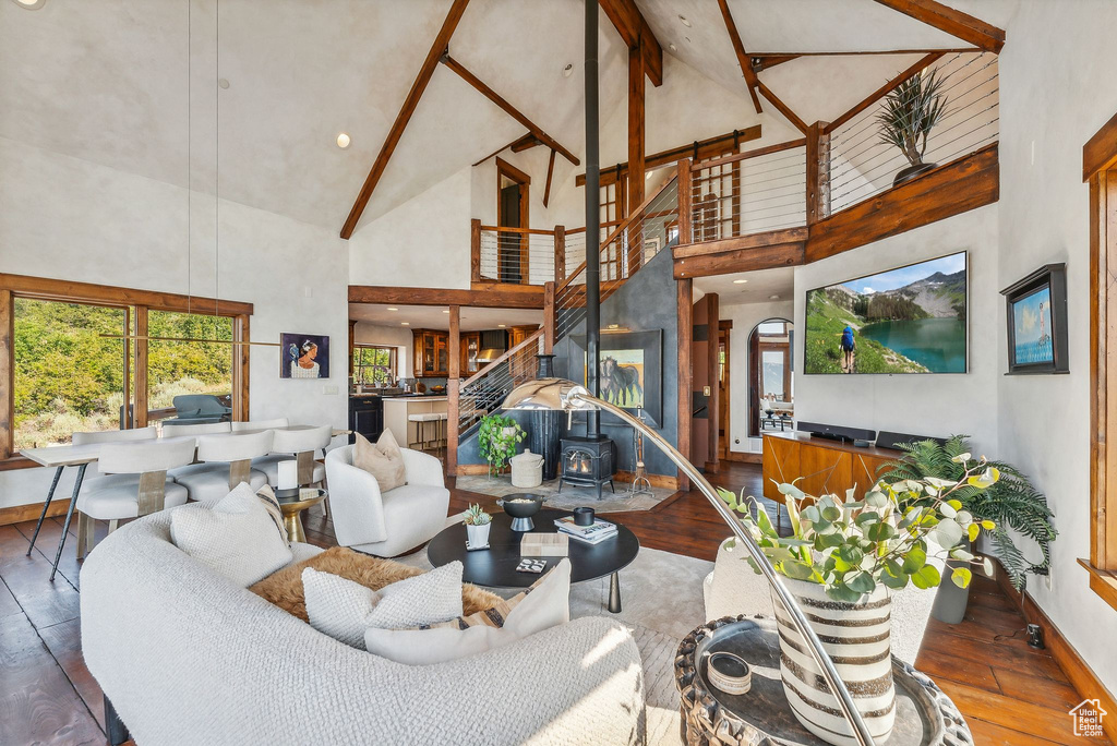 Living room featuring high vaulted ceiling, hardwood / wood-style floors, and a wood stove