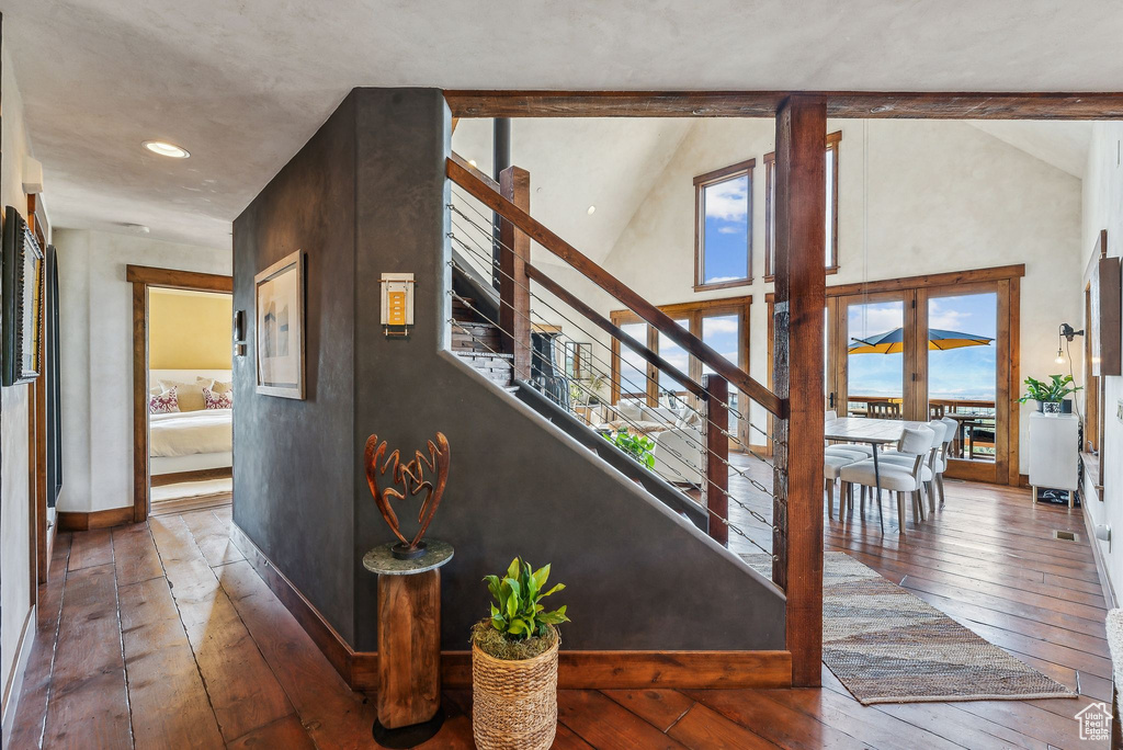 Staircase featuring wood-type flooring, high vaulted ceiling, and plenty of natural light