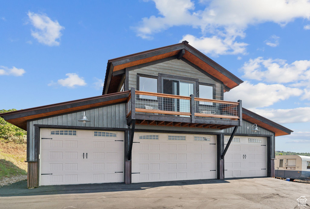 View of front of house featuring a garage and a balcony