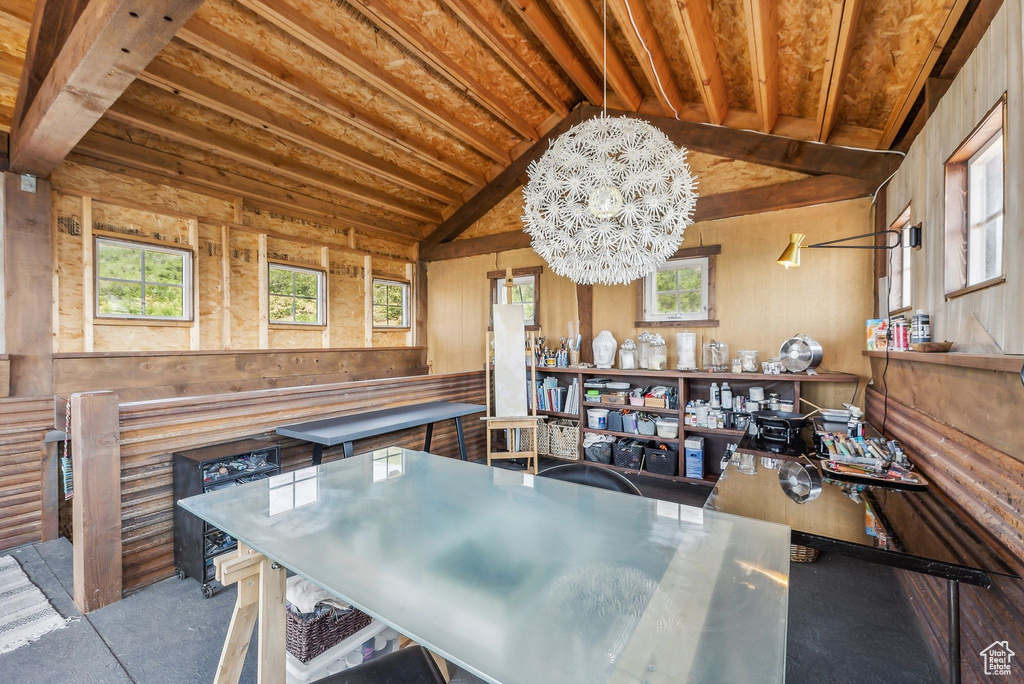 Dining room featuring a notable chandelier, lofted ceiling, and wood walls