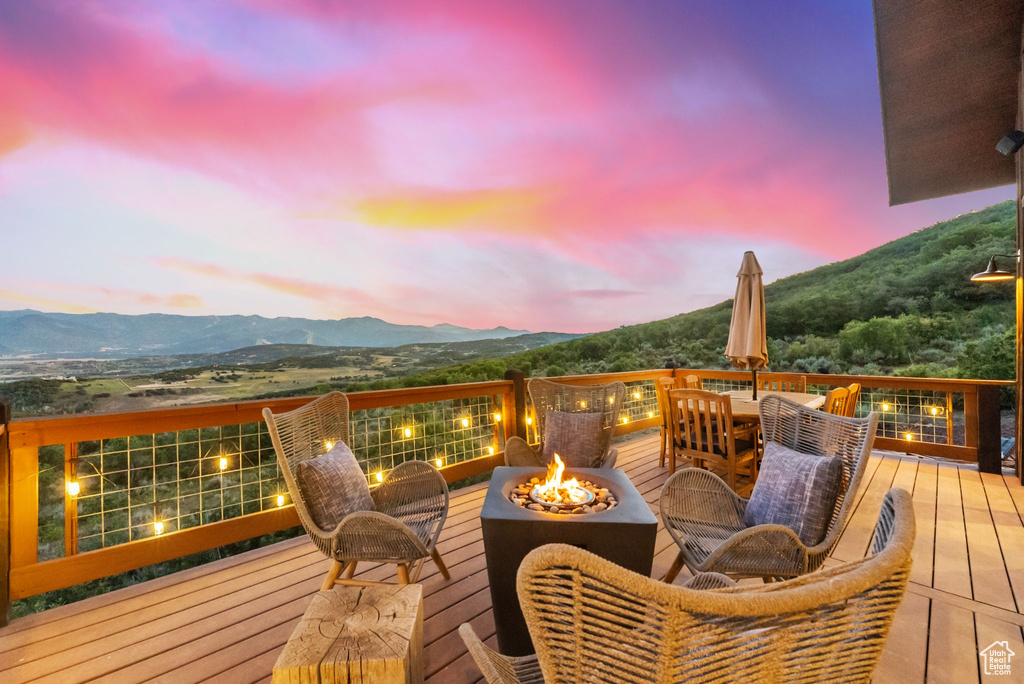 Deck at dusk with a mountain view and an outdoor fire pit