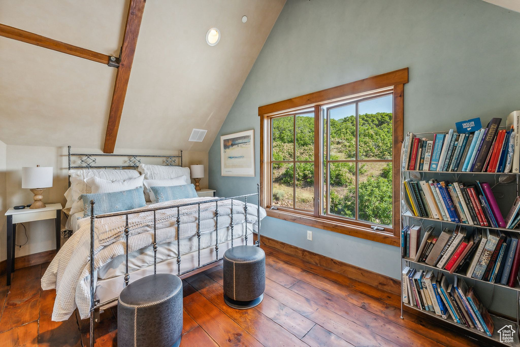 Bedroom with vaulted ceiling with beams and hardwood / wood-style floors