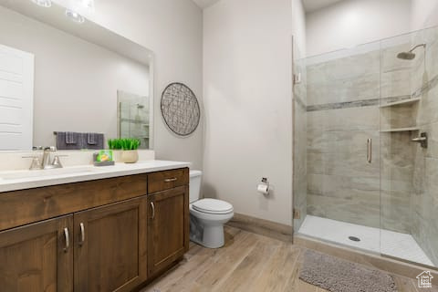 Bathroom featuring vanity, walk in shower, wood-type flooring, and toilet